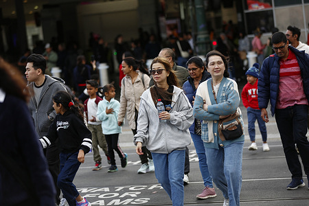Pedestrians walk through cold and windy conditions in Melbourne. Residents and visitors gather across Melbourne on Christmas Eve, as festive decorations, markets, and illuminated city streets draw crowds for seasonal celebrations.