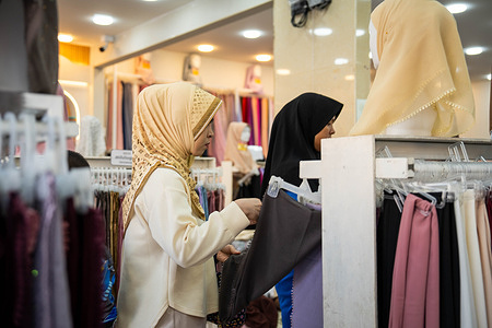 Women seen choosing hijabs inside a clothing shop ahead of Eid al-Fitr. Hijab and dress shops seen bustling on the eve of the celebration as locals prepare for Eid al-Fitr which the country has officially announced will fall on Saturday, March 21 2026.