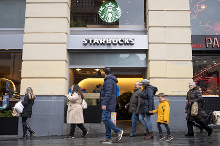 People walk past the American multinational chain, Starbucks Coffee, store in Spain.