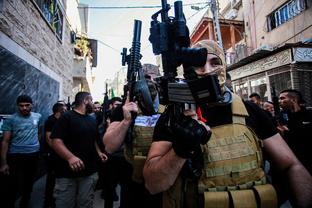 Armed Palestinian militants attend the funeral ceremony in Jenin refugee camp of a militant killed in clashes during an Israeli military raid.