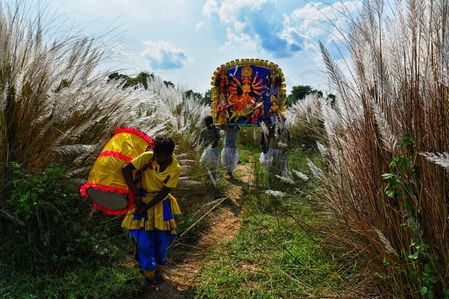 Porters are seen carrying an idol of Hindu goddess Durga to a Pandal (Temporary Platform for Worshiping of Idols) ahead of the Durga puja, the biggest Hindu Festival. The annual Durga Puja festival is uniquely marked by night-long Purulia Chhau dance performances recreating mythological battles between Goddess Durga and Mahishasura. Local artists wearing elaborate GI-tagged artisan masks lead vibrant village processions, combining sacred rituals with centuries-old tribal martial arts traditions.