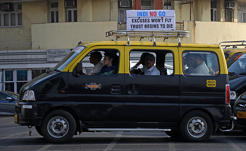 A taxi is seen passing near the poster placed above a restaurant criticising Indigo airlines in Mumbai. Country's biggest airline Indigo cancelled flights across the country leaving passengers stranded at the airport because of a shortage of pilots after it failed to plan adequately for new rules limiting on how many hours pilots work. Passengers had to wait at the airport feeling frustrated not knowing whether flights will resume or they will be alloted a seat in other airline. Many passengers got into arguements with the ground staff at the airport demanding refund of money leading to huge crowding at the airports across the country and fliers missing their personal and professional commitments.
