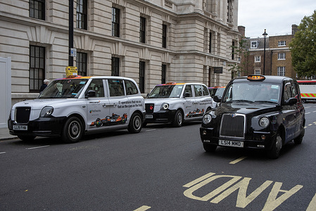 A black cab drives by the parked vehicles with advertisements on them near the Whitehall in London. The Freshworks is a leading IT software provider company. The recently announced sponsorship of the McLaren is advertised on some of the London's taxis.