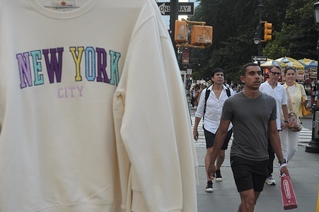 People walk past a vendor selling New York City souvenir clothing in Manhattan, New York City.