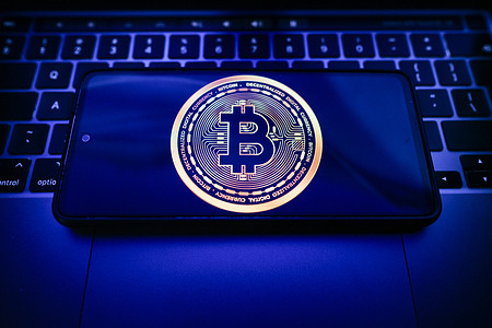 In this photo illustration, a Bitcoin logo is seen displayed on a smartphone on the top of a laptop.