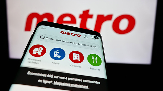 In this photo illustration, a cellphone with the webpage of Canadian retail company Metro Inc. is seen in front of business logo.