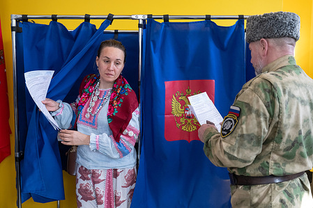A woman in traditional clothing leaves a voting booth at a polling station during Russia's three-day parliamentary elections.