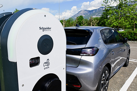 A car is bieng charged at Schneider Electric electric vehicle charging station. Schneider Electric electric vehicle charging station at Chambéry airport in France.