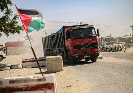 A Palestinian flag waving with a truck loaded with goods in the background, at the Kerem Shalom goods-crossing as Israel approved a series of measures to ease the blockade of the Gaza Strip, including expanding the fishing zone to 15 miles, opening the Kerem Shalom crossing to continue the commercial movement between Israel and the Gaza Strip, increasing the water quota for the Strip by 5 million cubic meters and increasing the quota of Gaza merchants to cross the Erez crossing in the northern Gaza Strip.