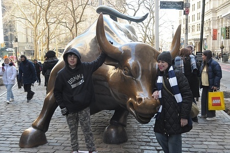 People take photos by the "Charging Bull" statue in the Financial District in Manhattan, New York City.