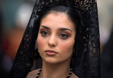 A 'mantilla' (a woman dressed in mourning clothes) of 'Estrella' brotherhood is seen taking part in the procession during the Holy Week celebrations. Thousands of people celebrate Holy Week waiting to see the brotherhoods and Easter processions in the streets of the city. Holy Week in Andalusia, which brings together thousands of devotees and faithful, is considered one of the most important religious and cultural celebrations in the region.