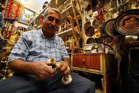 An Iraqi man cleans a copperware item to be sold in a shop in Safafeer Souq.