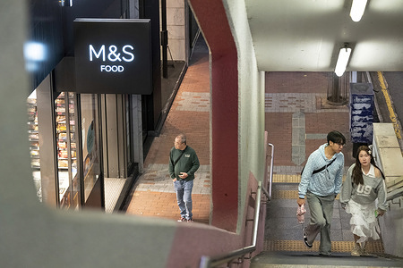 Pedestrians walk past the British multinational retailer Marks & Spencer (M&S) food section store seen in Hong Kong, China.