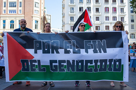 Activists hold a banner with the slogan: "For the end of genocide" during a rally organized by the "Stop the War" platform under the slogan "For Peace. End Genocide," to demand an end to Israeli attacks on Palestine in Madrid's Plaza de Callao.