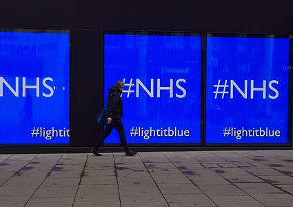 A man walks past the screens displaying 'NHS' at the Flannels store on Oxford Street in London.
The screens at the store were showing a series of artworks as part of the 'Light It Blue' campaign in support of the NHS during the coronavirus crisis.