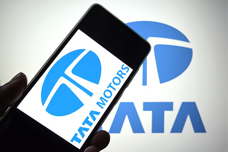 In this photo illustration, a TATA Motors logo is seen displayed on a smartphone with a TATA group logo in the background.