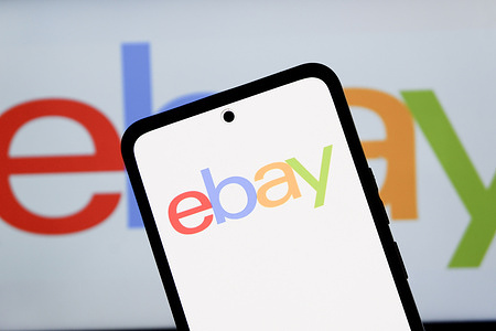 In this photo illustration, American multinational e-commerce company operating an online marketplace, eBay Inc. logo is seen displayed on a smartphone and in the background.
