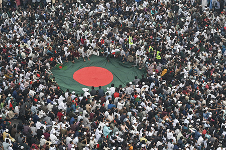 Thousands of people gather and hold Bangladesh's flag after the funeral ceremony of Sharif Osman Hadi, a student leader, who died after being shot in the head.