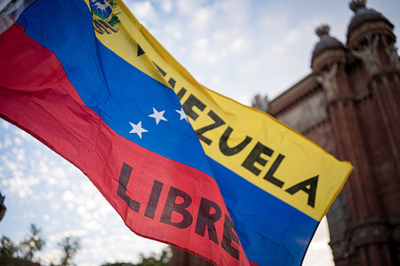 The flag of Venezuela is seen waving in front of the Arc de Triomf during the demonstration. People marched in cities all over Spain and the world after the leader of the Venezuelan opposition Maria Corina Machado, called for fresh protests against what she considers as an electoral fraud by President Nicolas Maduro.