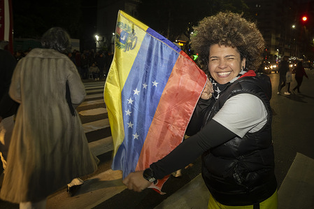 A young Venezuelan woman smiles and waves a Venezuelan flag at the passing cars. Venezuelan residents in Argentina vote at their embassy in the city of Buenos Aires, the only place authorized for the event. Of the 220,000 living in Argentina, 150,000 would have been able to vote, but only 2,638 will be able to do so due to the numerous obstacles imposed on Venezuelan migrants by the government of dictator Nicolás Maduro.