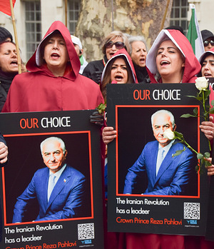 Women wear costumes from 'The Handmaid's Tale' and hold pictures of Reza Pahlavi during the demonstration outside Downing Street. Pro-monarchy protesters gathered in protest against the Islamic Republic, in support of Crown Prince of Iran Reza Pahlavi, and calling for a return to monarchy in Iran, as USA and Israel continue their attacks.