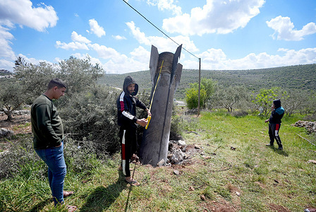 A Palestinian man measures the length of a fragment of an Iranian missile that landed in farmland near the village of al-Harith in the northern West Bank. The fragment fell in the area after Israel intercepted a barrage of Iranian missiles fired toward it. Since the United States and Israel launched airstrikes against Iran, the conflict has spread across the Middle East, with reports of casualties in various countries in the region.