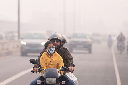 People ride on a bike along a road amid smoggy conditions in New Delhi. As the city's air quality declined to absolutely horrible levels, residents of New Delhi, the capital of India, woke up to a heavy layer of smog. Falling temperatures, smoke, dust, low wind speed, vehicle emissions, and burning crop stubble are the main causes of the hazardous air that the northern states and the nation's capital face every year from October to January.