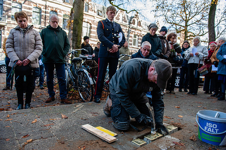 People are seen watching how a man is placing the stones on the pavement. As part of a new tradition to remember the Jewish victims of the Nazi regime, twenty-seven Stolpersteine were placed on the pavement in front of the house where the victims lived or worked, during a solemn ceremony attended by the relatives of the victims. Stolpersteine ​​are coblestones covered at the top with a brass plaques to remember the persecuted and murdered Jews who became victims of the Nazi regime. About 450 Jewish citizens of Nijmegen did not survive during the Second World War.