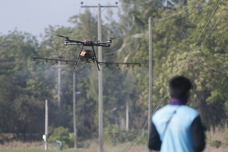 A Thai drone controller seen using a drone to spray fertilizer on a rice field.