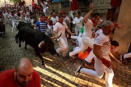 Runners fall to the ground as the Victorino del Río bulls pass by during the third bull run of the 2026 San Fermín festival in Pamplona.