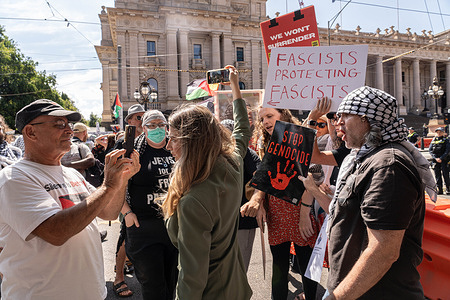 A protester seen closely crowding around the channel 7 news reporter, (who is filming with a mobile phone) yelling "Tell the truth, Zionist supporter" as they push her away from the crowd during the demonstration. Melbourne channel 7 news reporter was harassed and pushed out of the crowd at 'anti zionist' rally by Pro Palestine protesters.