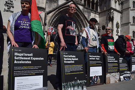 Protesters stand with placards describing what they call 'a timeline of a genocide' during a demonstration outside the Royal Courts of Justice as the government appeals the high court ruling that the ban on the activist group Palestine Action is unlawful.