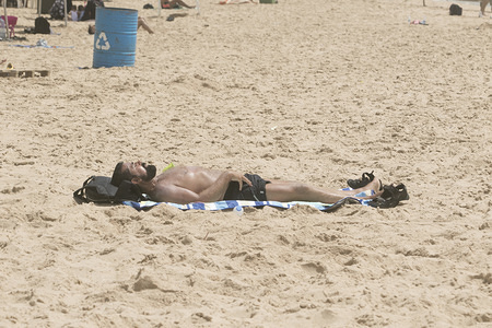 A man sunbathes at the beach in Beirut during a sweltering day as temperatures exceed 40 degrees Celsius.