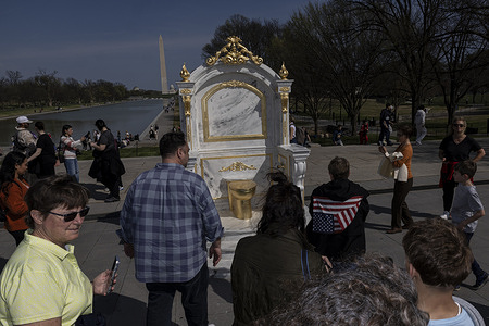 Visitors and tourists take photos of a gold-painted, faux-marble toilet statue titled “A Throne Fit For A King”, which is installed near the Lincoln Memorial on the National Mall. The satirical installation references reports of renovations to the bathroom connected to the Lincoln Bedroom at the White House during former President Donald Trump’s tenure. The unexpected display drew attention from visitors and sightseers.