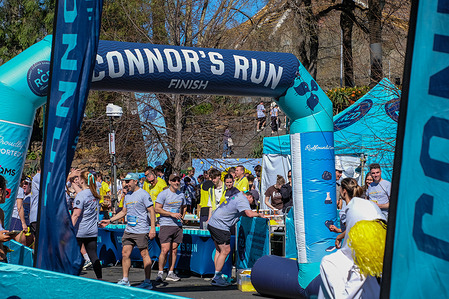 Event participants seen at the finishing line during Connor's Run charity run in Alexandra Gardens. Connor's Run is an annual charity event that has become Australia's largest fundraiser for pediatric brain cancer. The event was created by the Robert Connor Dawes Foundation in memory of Robert "Connor" Dawes, who passed away from an ependymoma brain tumor at the age of 18 in 2013. The main event takes place in Melbourne with three course options: 18.8 km, 9.6 km, and 3 km, each symbolizing meaningful aspects of Connor's life. Funds raised support the Robert Connor Dawes Foundation’s "brain matters" projects, which focus on research, care, and initiatives to help young people with brain cancer.