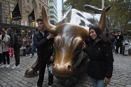 People take photos by the "Charging Bull" statue in the Financial District in Manhattan, New York City.