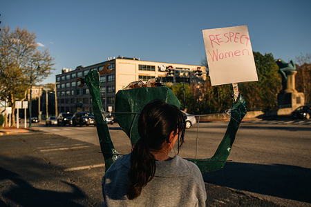 A protester holds a placard during the demonstration. Roughly 100 protesters gathered at the major intersection of Main and High Streets in Willimantic to voice their opposition to the administration's recent executive actions. The peaceful demonstration, organized by local advocacy groups, featured participants holding signs and chanting slogans to call for policy changes and greater government accountability.