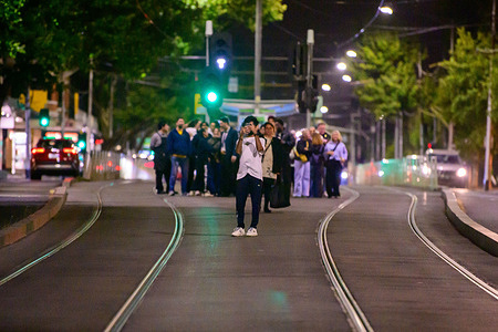 A crowd gathers on tram tracks in Melbourne’s CBD to photograph New Year’s Eve celebrations as traffic is restricted across the city. Large crowds filled the Melbourne CBD on New Year’s Eve 2025 as revellers gathered in public spaces, entertainment precincts, and transport hubs to celebrate the arrival of the New Year. Trams and trains carried passengers late into the night as people moved between events and social gatherings. Despite a strong security presence, the atmosphere across the city remained relaxed as Melbourne residents and visitors marked the end of the year.