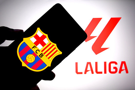 In this photo illustration, the FC Barcelona logo is seen displayed on a smartphone with the La Liga logo in the background.