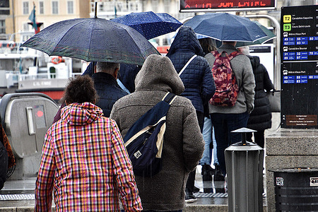 People with umbrellas are seen in the rain at the entrance to the metro station in Marseille.