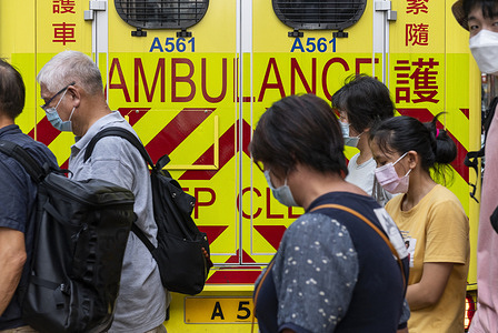 Commuters walk past an ambulance stationed on the street in Hong Kong.