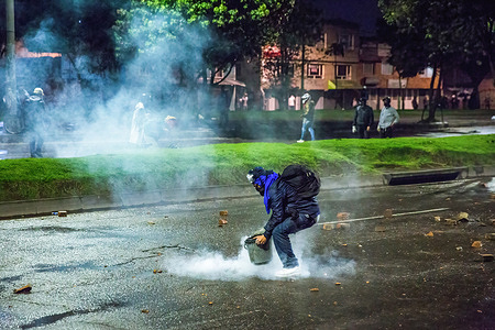 A protester seen extinguishing a tear gas canister by covering it with a bucket during the demonstration.June 28th marked two months of protests in Colombia. In many cities of the country, blockades and demonstrations took place. In response, the government deployed anti-riot police, sparking clashes that left hundreds of protesters injured.