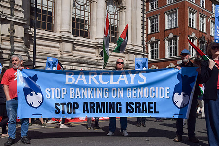 Pro-Palestine protesters stand with a banner calling on Barclays to 'Stop banking on genocide' during the demonstration outside Queen Elizabeth II Centre in Westminster as Barclays holds its annual general meeting (AGM). The protesters are calling on the banking giant to cut its alleged financial ties to Israeli weapons companies.
