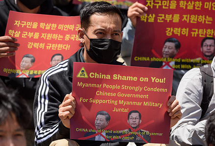 Myanmar protester living in South Korea holds a placard in front of the Seoul train station in Seoul during a protest against China's support for Myanmar's military government.