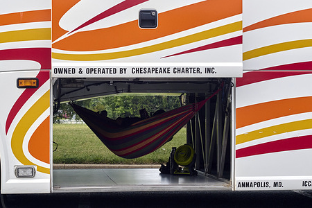A bus driver rests in a hammock inside the cargo hold of a charter bus in Kent Island.