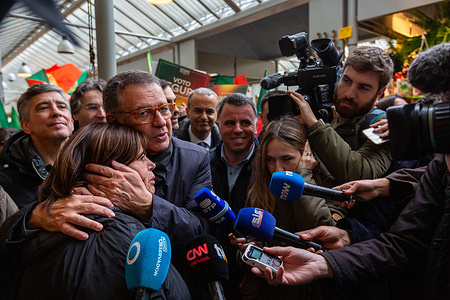 José Seguro embraces a supporter during a press moment inside Mercado do Bolhão, Porto, as journalists and cameras capture the emotional exchange on the final day of his presidential campaign.
