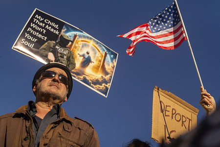 Demonstrators gather with placards during a protest calling for an end to federal immigration enforcement operations and U.S. attacks on Venezuela.