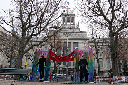 A Pussy Riot member Taso Pletner and an anonymous artist stand over a painting of a rainbow flag inside transparent plastic cabins during a demonstration in support of LGBTQ+ people outside the Russian Embassy. Pussy Riot activist Taso Pletner staged a demonstration in Berlin in collaboration with Quarteera, a Russian-speaking LGBTQ+ nonprofit registered in Germany. Quarteera, founded in 2011, represents gay, lesbian, bisexual, and transgender people and their allies within the Russian-speaking community. The performance marked the anniversary of the Russian authorities’ decision to label the “international LGBT movement” as an extremist organization and symbolized the erasure of LGBTQ+ visibility in Russia.