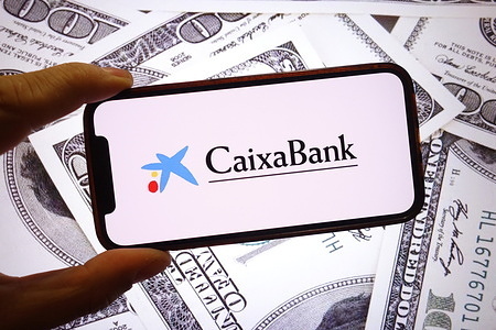 In this photo illustration, the CaixaBank company logo is seen displayed on a smartphone screen.