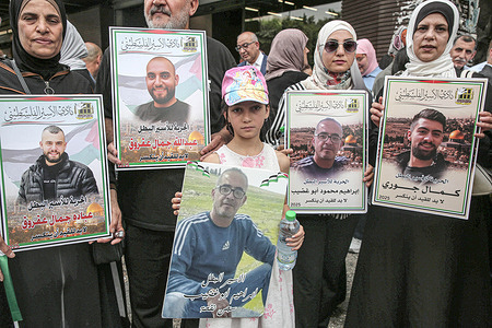Families of Palestinian prisoners hold portraits of their imprisoned relatives during a solidarity rally demanding a prisoner exchange agreement between the Israeli government and Hamas.